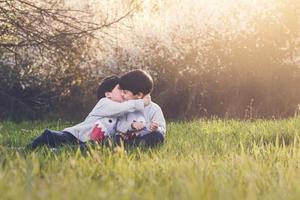 hermanos abrazándose sentados en el campo foto