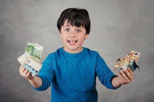 niño sonriente con billetes de euro sobre fondo gris foto