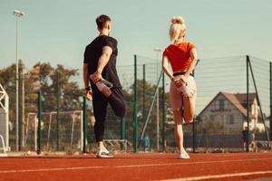 girl and a guy doing a warm-up before sports exercises at the school stadium