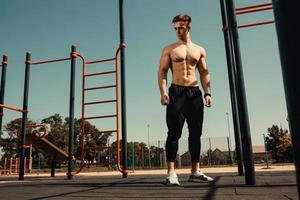 guy with a beautiful athletic body posing while standing next to the horizontal bars photo