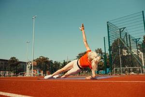 Young couple doing sports in the stadium lying on yoga mats photo