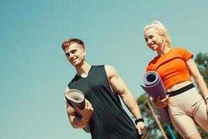 young couple walking down the street with sports mats in their hands photo