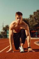 young guy with athletic body getting ready to run photo