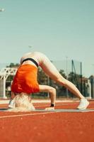 joven rubia aprende a mantener el equilibrio en una parada de cabeza y de manos foto