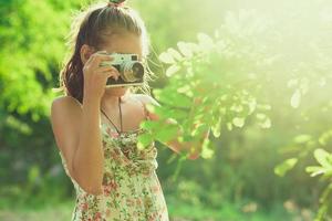 Beginning photographer. A little girl takes pictures of a tree on her film photo camera