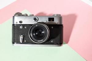 Old film photo camera on a bright pink background