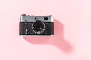 Old film photo camera on a bright pink background