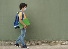covid-19, niño con mascarilla médica y mochila yendo a la escuela foto