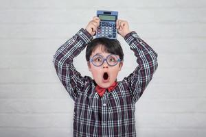 Happy student showing calculator over his head photo