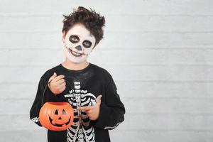 feliz halloween niño divertido en un disfraz de esqueleto con calabaza de halloween foto