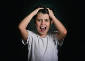 angry and stressed child with his hands on his head photo