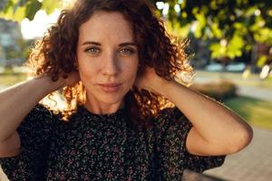 Portraits of a charming red-haired girl with freckles and a pretty face. The girl poses for the camera in the city center. She has a great mood and a sweet smile photo