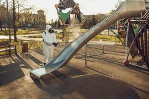 Cleaning and Disinfection on the playground in the sity complex amid the coronavirus epidemic Teams for disinfection efforts Infection prevention and control of epidemic Protective suit and mask photo