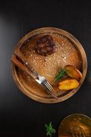 filet mignon medium rare served on a wooden plate with baked potatoes