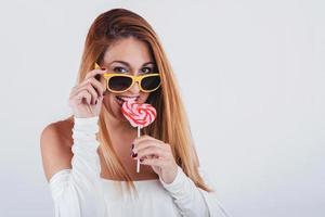 Portrait of smiling Young woman with heart shaped lollipop and sunglasses photo