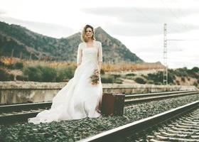 bride with a red suitcase on the train tracks photo