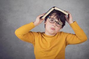 sad and pensive boy with a book on his head photo