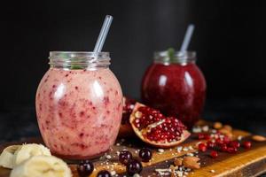 batidos recién preparados de plátano con granada y plátano con mora en botella. dieta, estilo de vida saludable foto