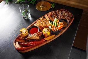 Josper set of pork ribs, chicken fillet, ribeye steak, hunting sausages, corn, potatoes and fresh vegetables photo