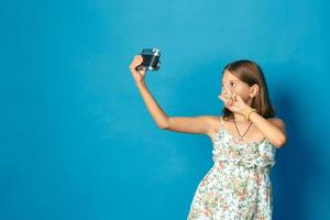 hermosa niña sonriente con dientes blancos sosteniendo una cámara y haciendo selfie foto