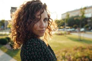 retratos de una encantadora chica pelirroja con una cara linda. chica posando para la cámara en el centro de la ciudad. ella tiene un estado de ánimo maravilloso y una sonrisa encantadora foto