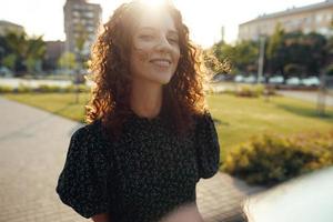Portraits of a charming red-haired girl with freckles and a pretty face. The girl poses for the camera in the city center. She has a great mood and a sweet smile photo