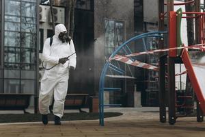 Cleaning and Disinfection on the playground in the sity complex amid the coronavirus epidemic Teams for disinfection efforts Infection prevention and control of epidemic Protective suit and mask photo