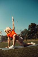 Beautiful blonde doing stretching on the lawn of a football field photo