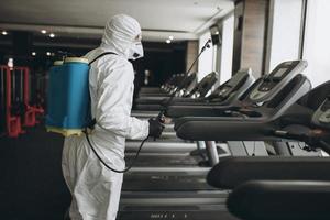 Cleaning and Disinfection in crowded places amid the coronavirus epidemic Gym cleaning and disinfection Infection prevention and control of epidemic. Protective suit and mask and spray bag photo