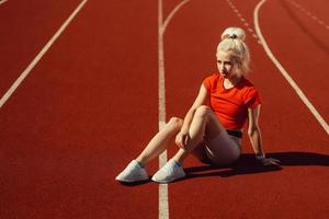 adorable blonde sits on a jogging track photo