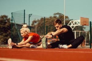 girl and a guy doing a warm-up before sports exercises at the school stadium photo