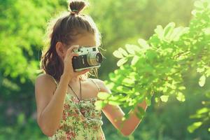 Beginning photographer. A little girl takes pictures of a tree on her film photo camera