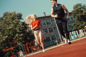 Young sports couple running in the stadium on the running track