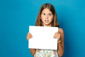 beautiful smiling child  girl with white teeth holding in hands white blank copy space for the announcement photo