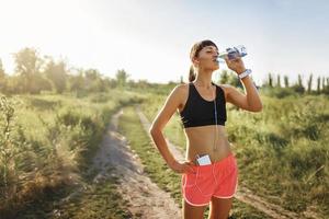 girl in headphones drinking water after jogging photo