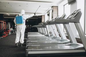 Cleaning and Disinfection in crowded places amid the coronavirus epidemic Gym cleaning and disinfection Infection prevention and control of epidemic. Protective suit and mask and spray bag photo