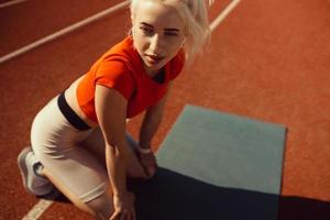 close-up portrait of a beautiful blonde who is sitting on a jogging track photo