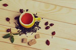 taza de té con rosas de cadera, sobre mesa de madera. una taza hecha de limón real foto