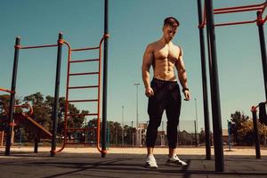 guy with a beautiful athletic body posing while standing next to the horizontal bars photo