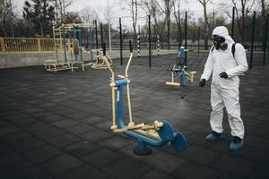 Cleaning and Disinfection on the playground in the sity complex amid the coronavirus epidemic Teams for disinfection efforts Infection prevention and control of epidemic Protective suit and mask photo