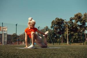 Beautiful blonde doing stretching on the lawn of a football field photo