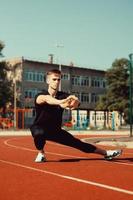 young guy doing warm-up before sports exercise at school stadium photo