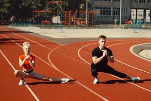 chica y un chico haciendo un calentamiento antes de los ejercicios deportivos en el estadio de la escuela foto