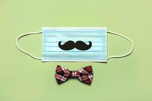 happy Father's Day. Protective surgical mask with false mustache and bow tie.Coronavirus epidemic concept photo