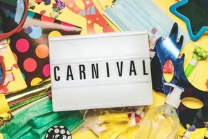 concepto de carnaval durante covid-19.lightbox con la palabra carnaval, junto a máscaras quirúrgicas protectoras, máscara de carnaval y botella de desinfectante.concepto de epidemia de coronavirus foto