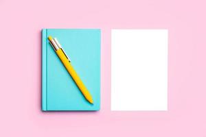 escritorio de trabajo con bloc de notas azul, bolígrafo amarillo y papel blanco con fondo de espacio de copia foto