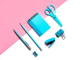 Flat Lay top view  of scissors, pencil, paper clips,stapler,pencil sharpener, pen with blue note pad.School stationery concept photo