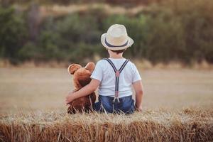 Boy hugging teddy bear in the wheat field photo