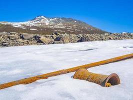 Old rails lead into water of frozen lake Vavatn Hemsedal. photo