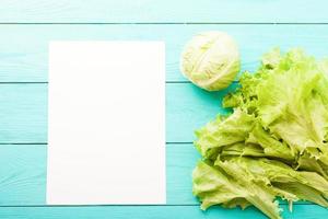 Cabbage and lettuce with recipe paper and copy space on blue wooden table. Top view photo